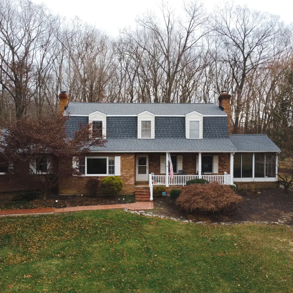 A brick colonial with three dormers and a new grey roof