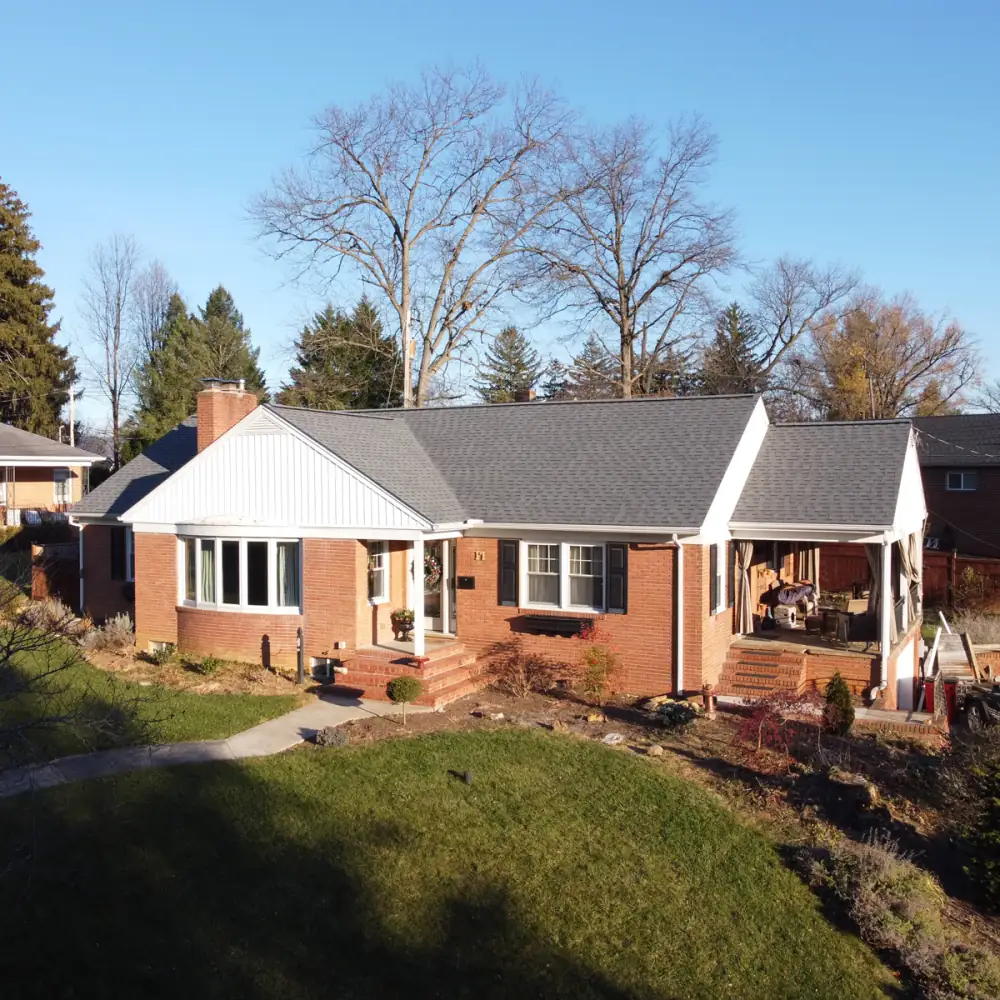 A brick rancher with a white gable and a new roof, seen from the lawn