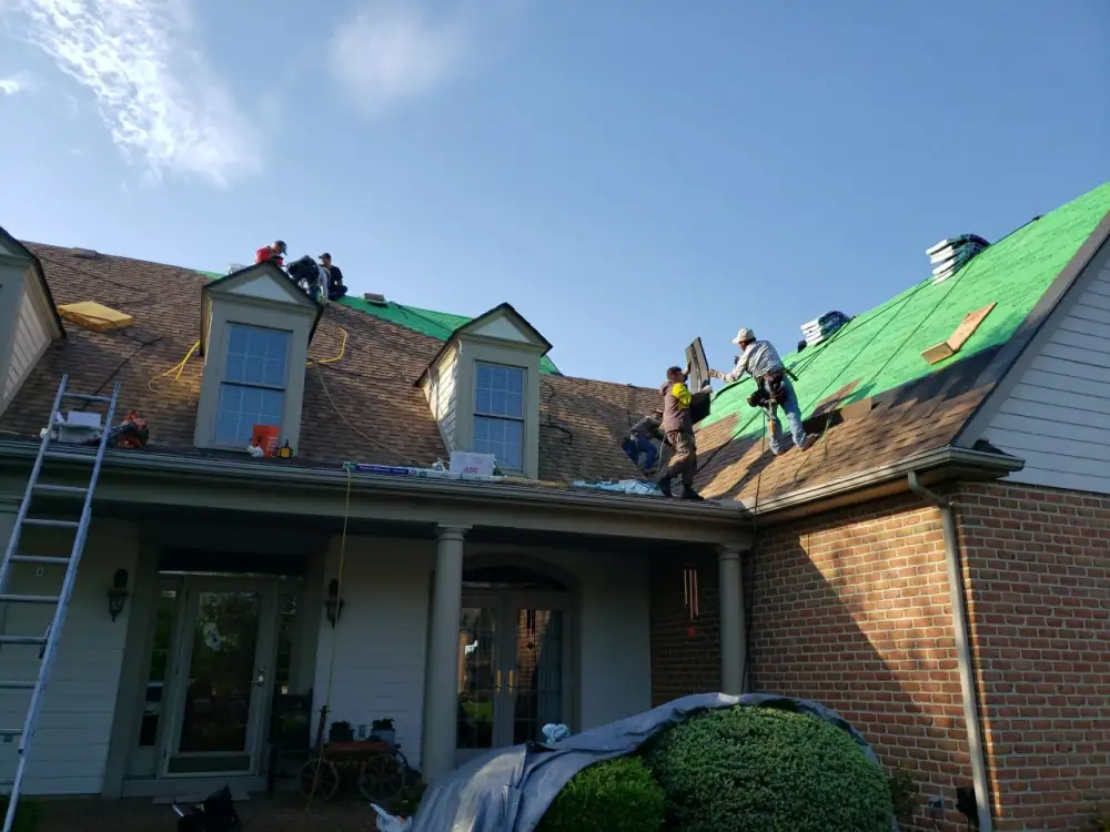 The crew laying new underlayment around dormers on a brick house