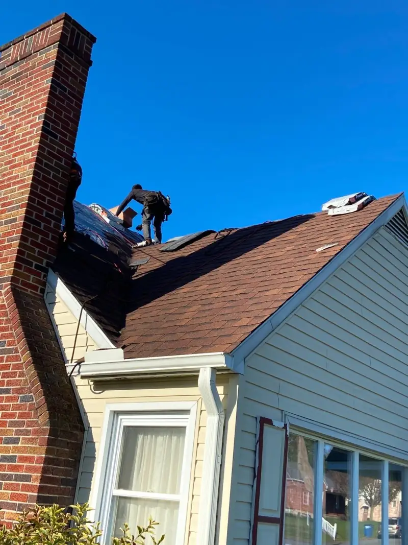 New brown shingles beside the brick chimney on Le's house