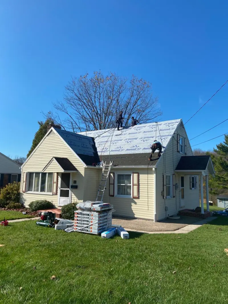 The crew on Le's yellow Cape Cod, with new underlayment on the roof
