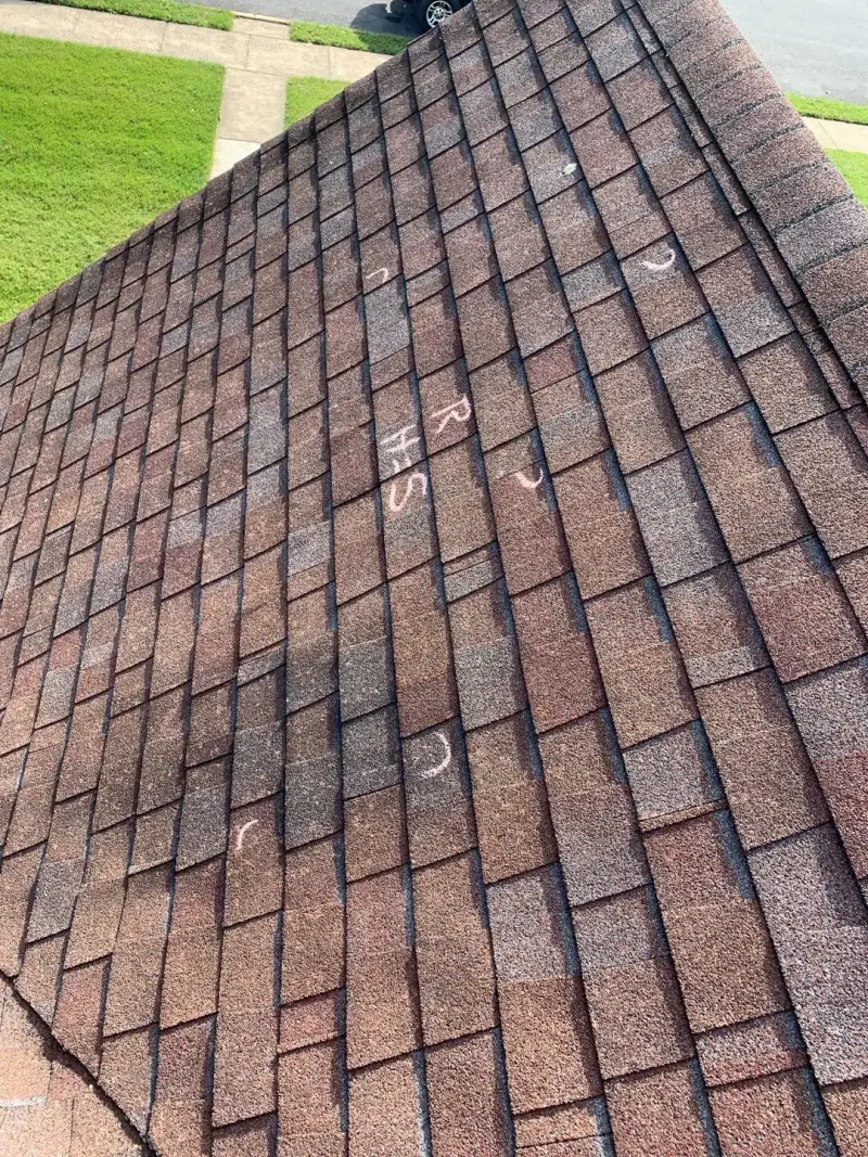 Brown shingles with chalk circles marking hail strikes
