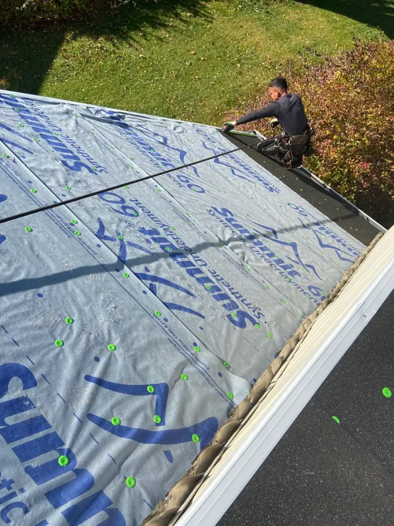 A roofer laying underlayment beside the eave