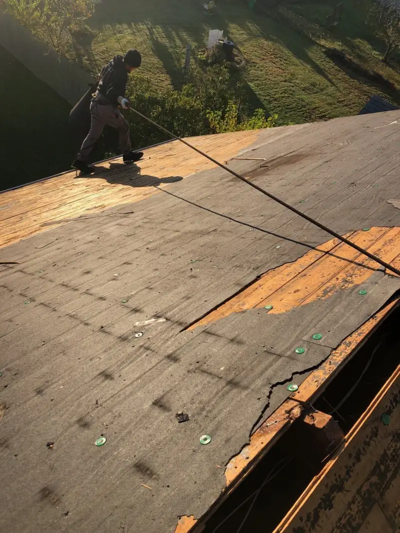 A roofer working on the bare deck of Sean's roof