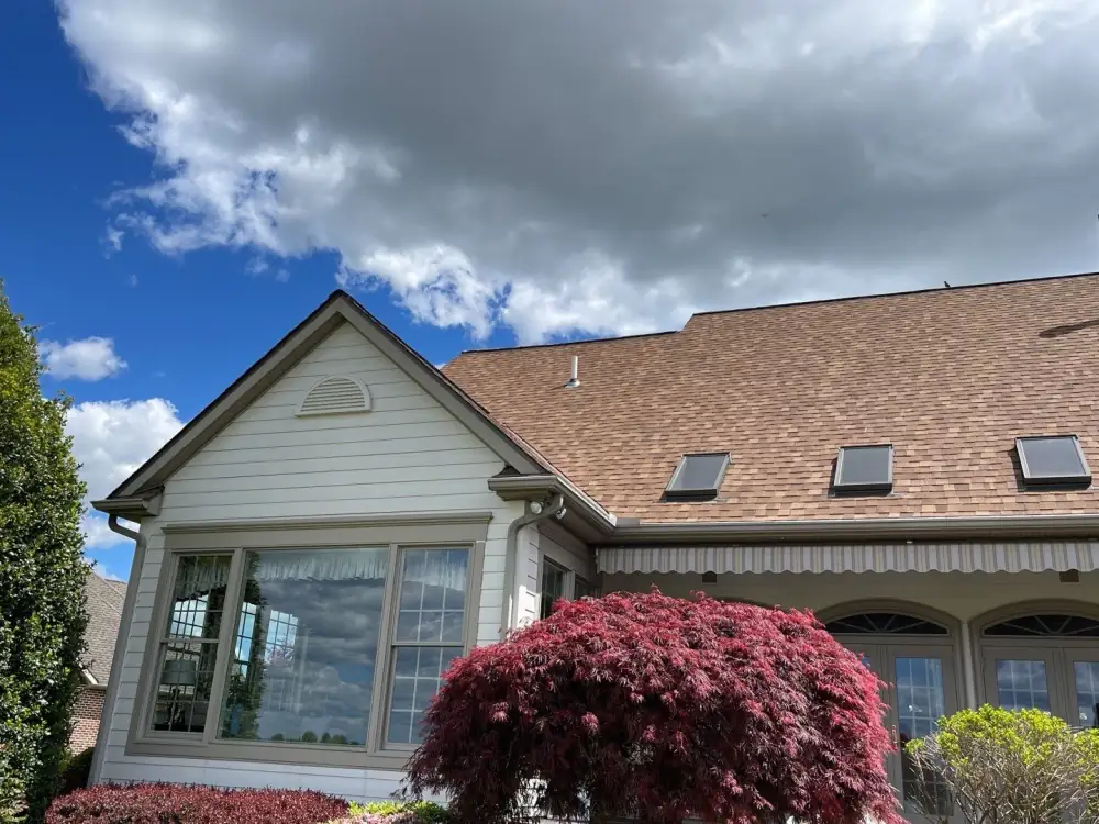 A house with four skylights and a new brown shingle roof under a blue sky