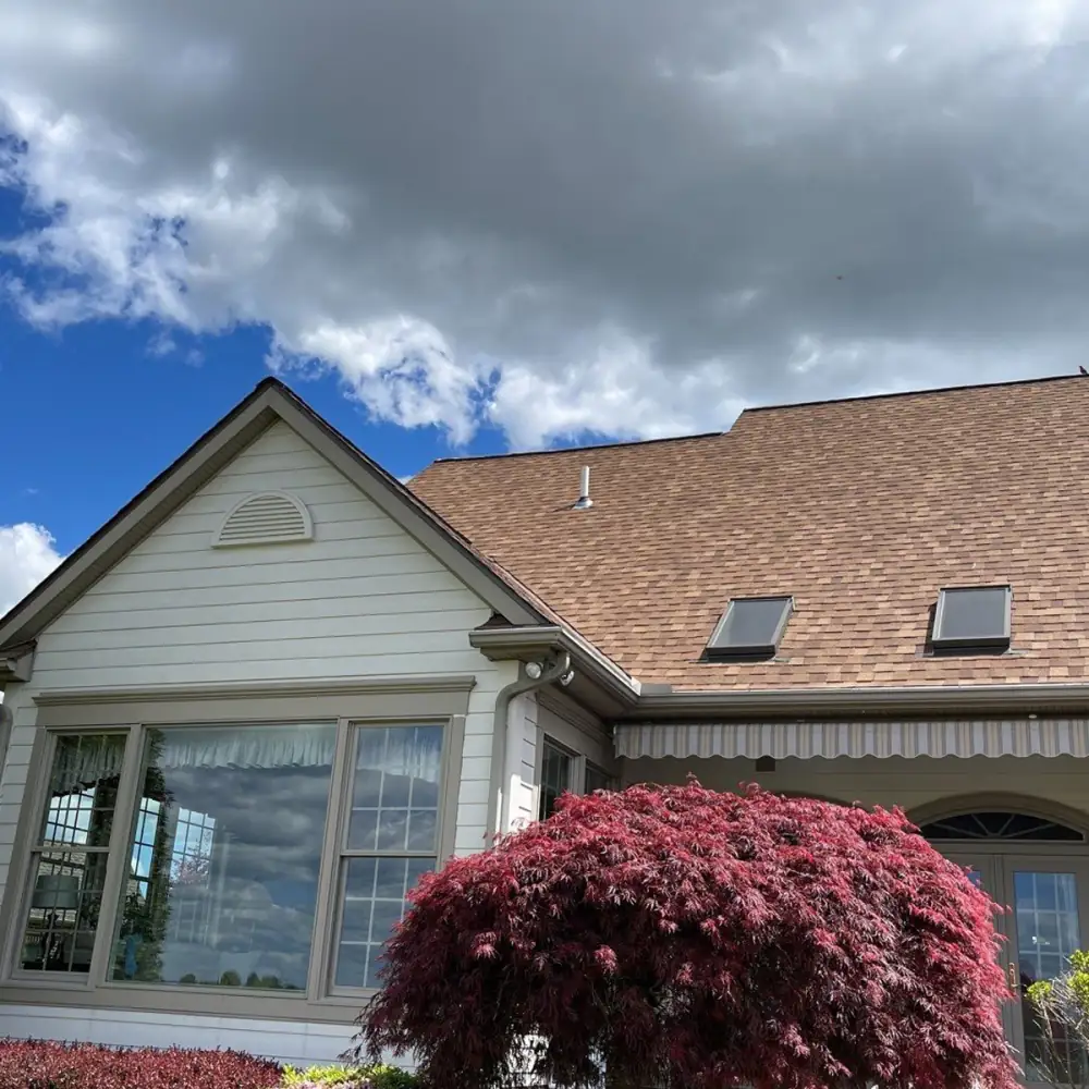 A house with skylights and a new brown roof under a cloudy sky